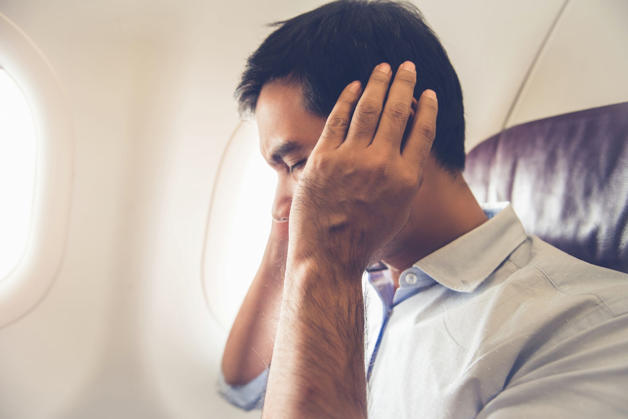Passager tenant ses oreilles à cause de la pression lors du décollage d’un avion